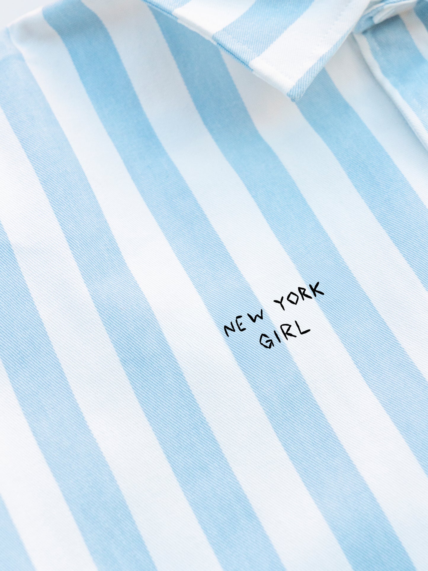 Woman wearing a striped shirt with a New York Girl embroidery