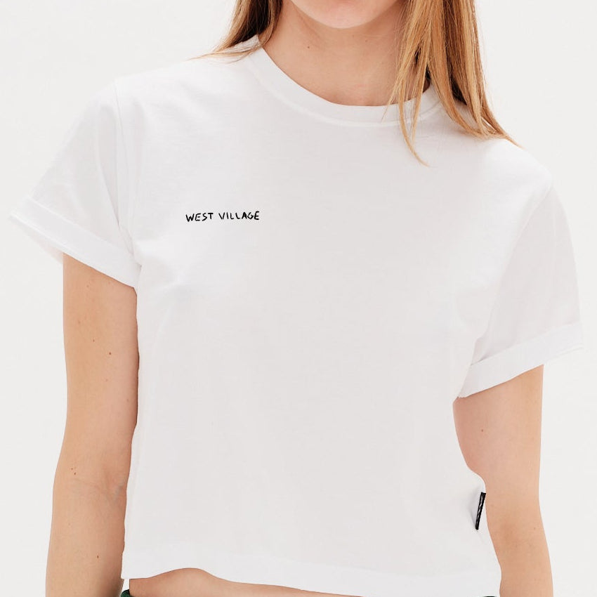 Woman wearing a white t-shirt with a West Village embrodery
