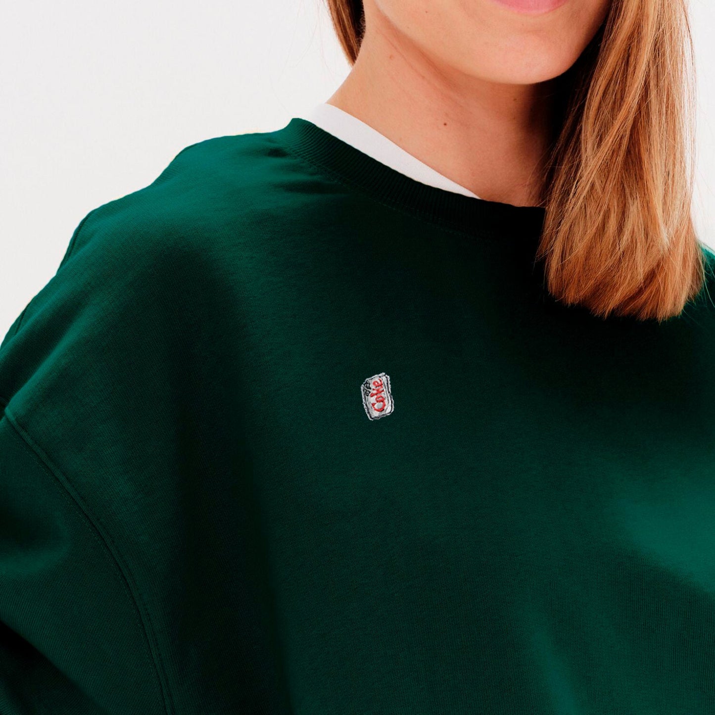 Woman wearing a green sweatshirt with a diet coke embroidery
