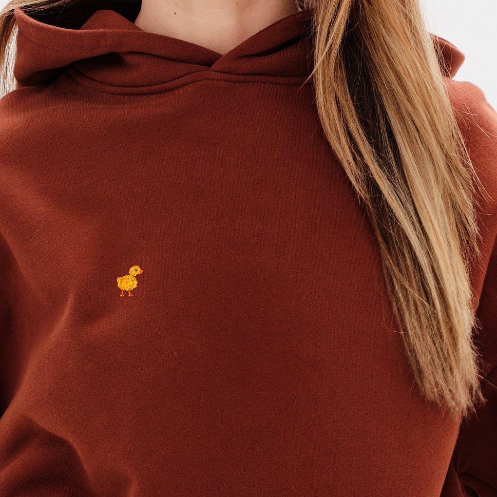 Woman wearing a premium brown hoodie with a duck embroidery