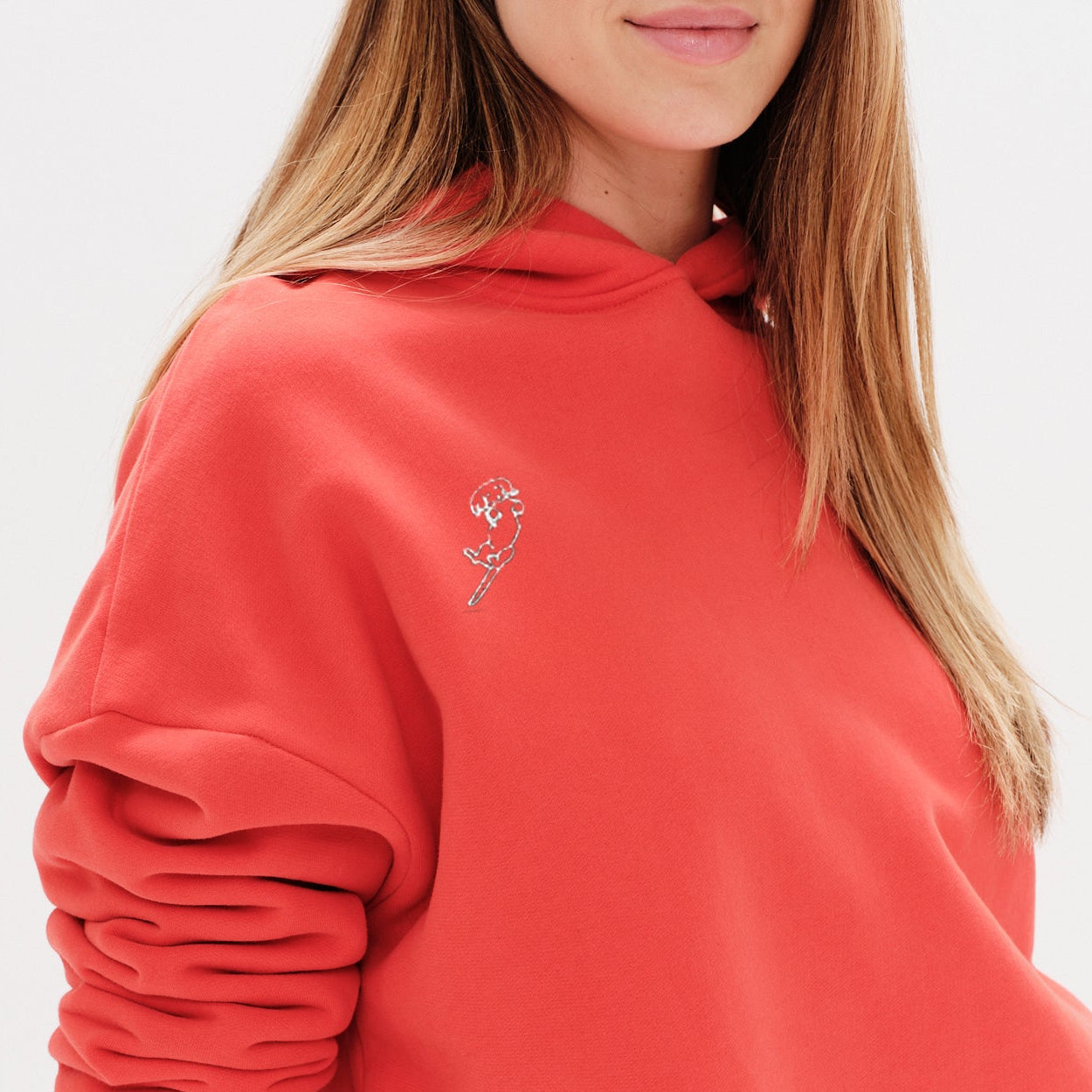 Person wearing a red hoodie with a wiener dog embroidery design