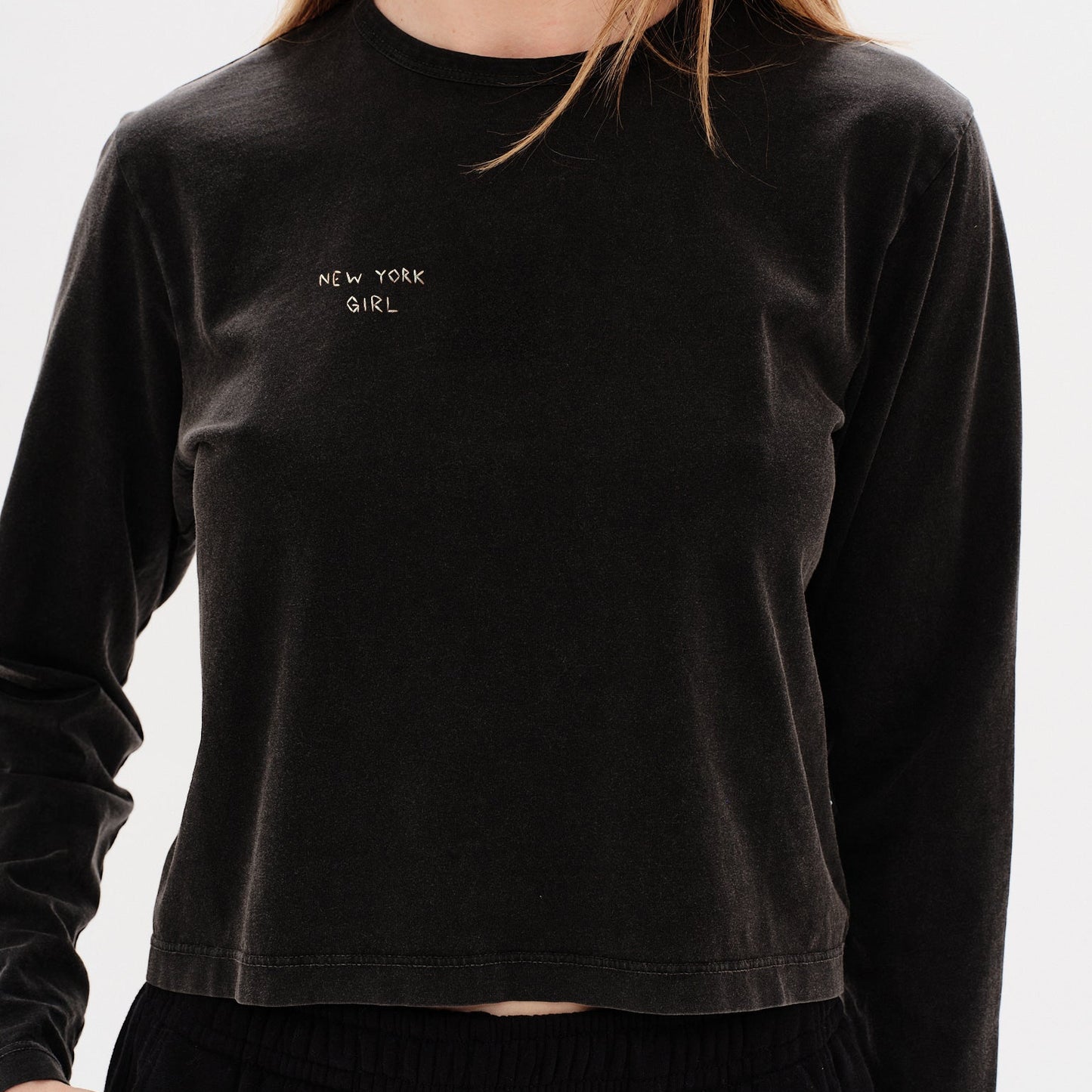 Woman wearing a black long-sleeve t-shirt with 'New York Girl' embroidery