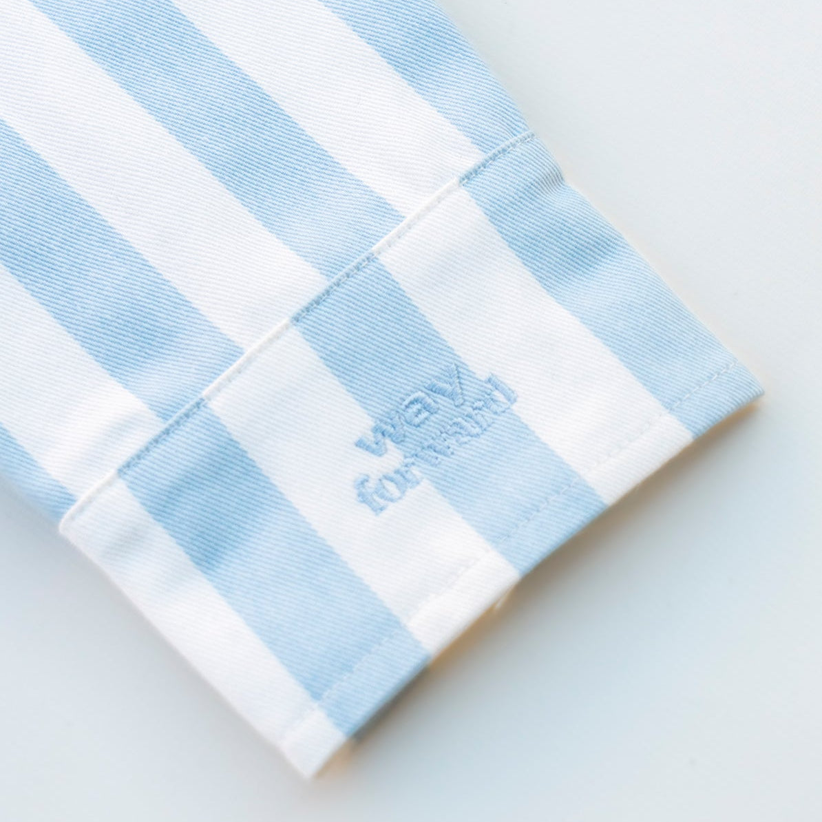 Blue and white striped shirt with embroidered text on a light blue background