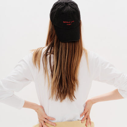 Person wearing a white sweatshirt, beige hoodie, and black cap with text on a light gray background