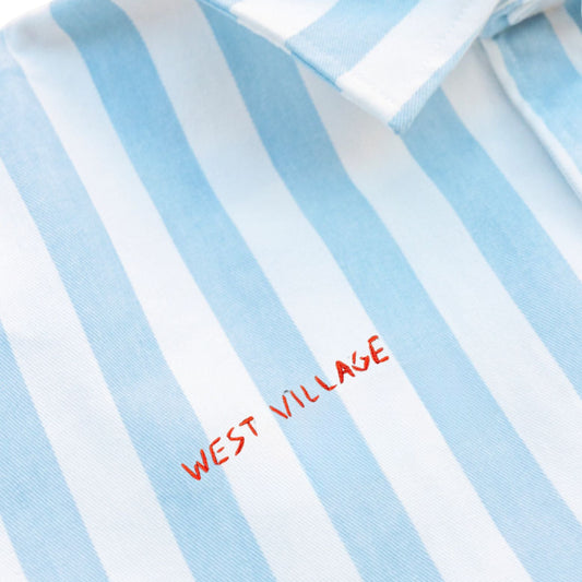 Close-up of a blue and white striped shirt with 'West Village' embroidery.