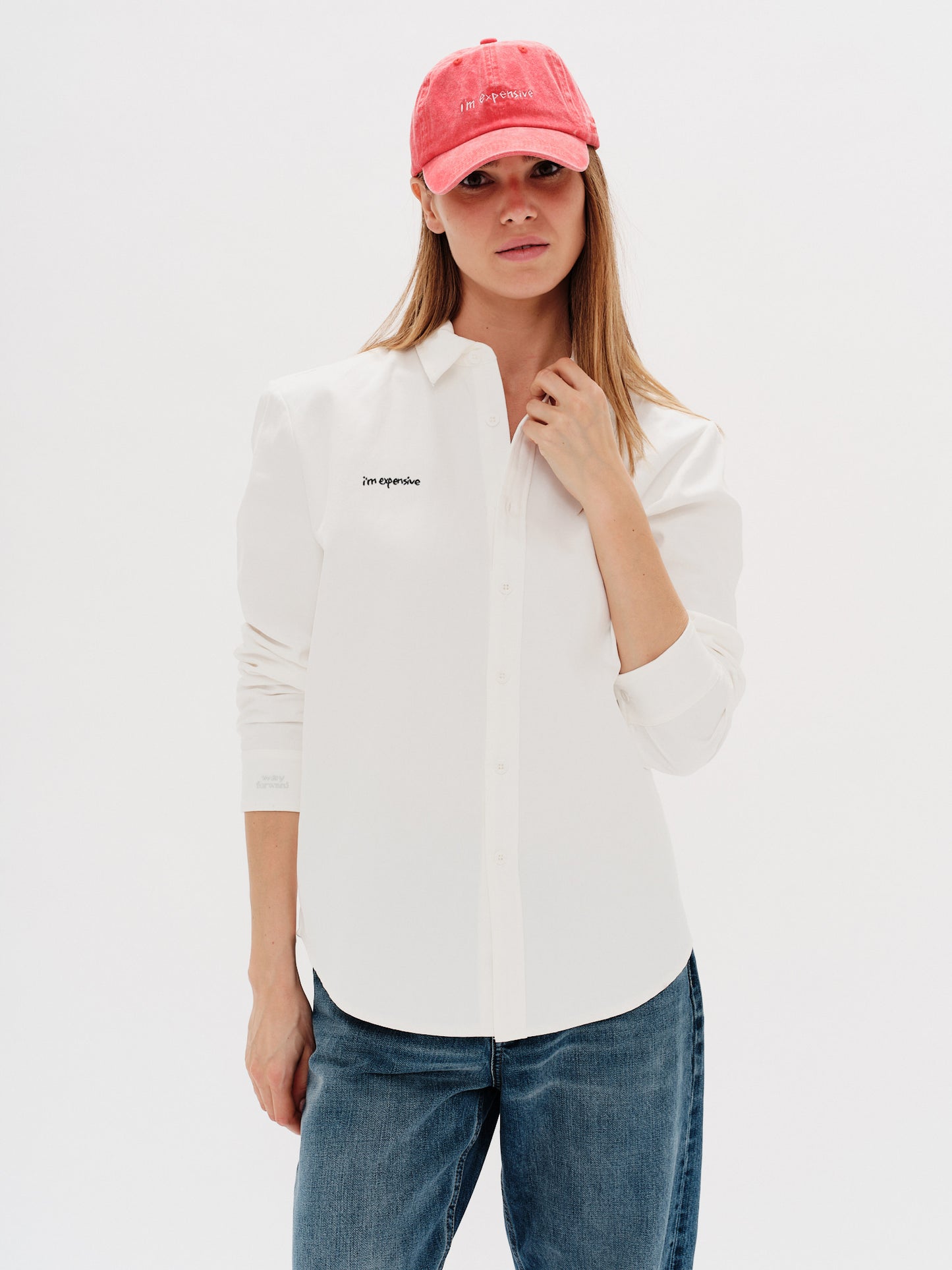Woman wearing a white shirt with a I'm Expensive embroidery