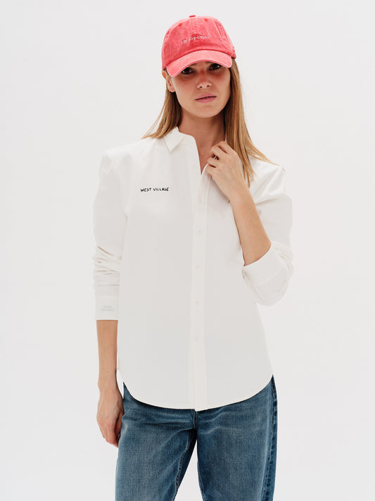 Woman wearing a white shirt with West Village embroidery