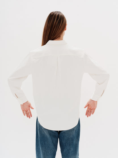 Woman wearing a white shirt with West Village embroidery