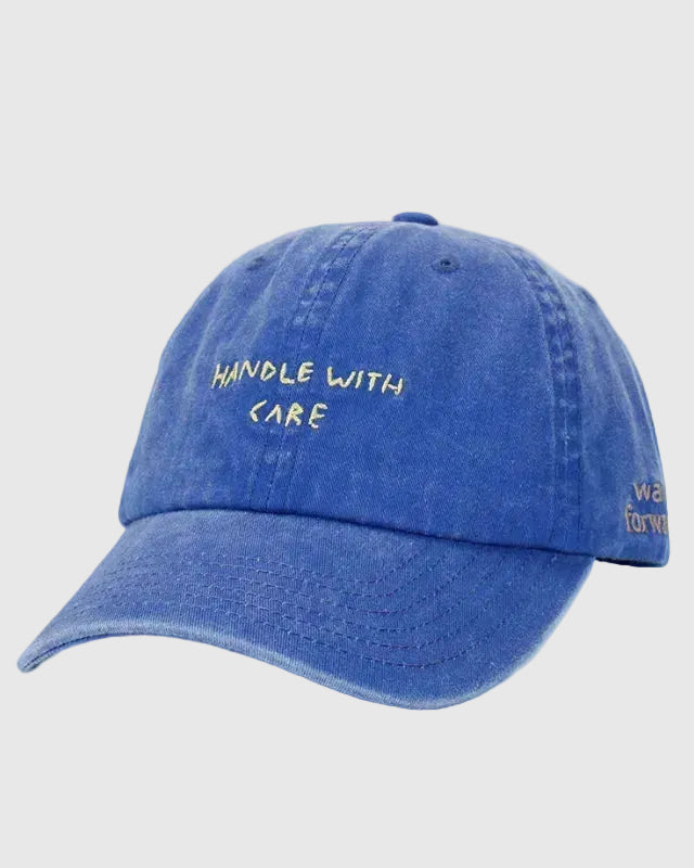 Blue cap with 'HANDLE WITH CARE' embroidered text .
