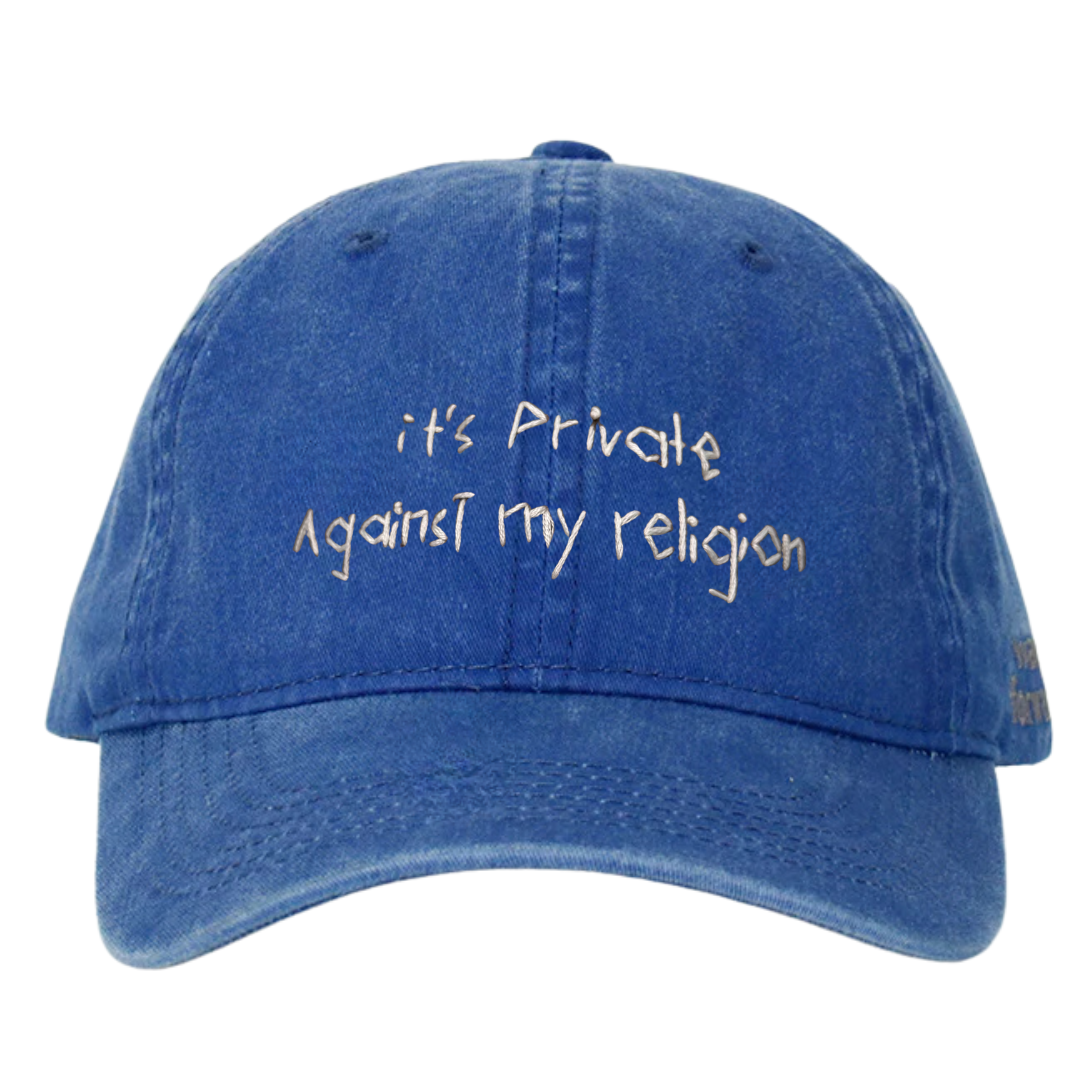 A blue wash baseball cap with white text 'it's private against my religion' embroidered on the front.