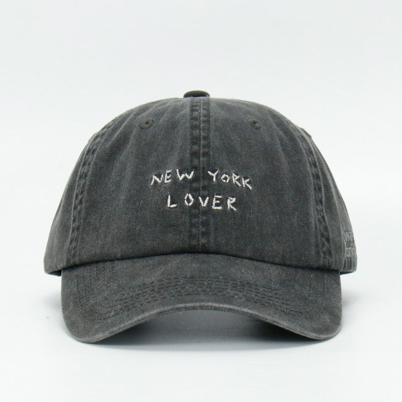 A black wash baseball cap with 'NEW YORK LOVER' embroidered on the front.