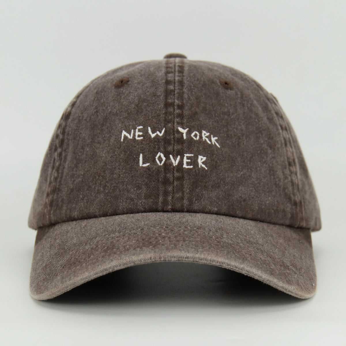 A brown wash baseball cap with 'NEW YORK LOVER' embroidered on the front.