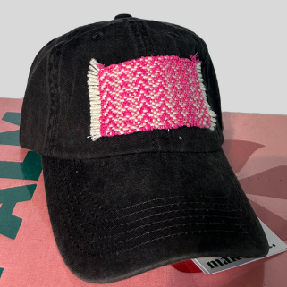 A black baseball cap with a pink patch on the front on a surface.