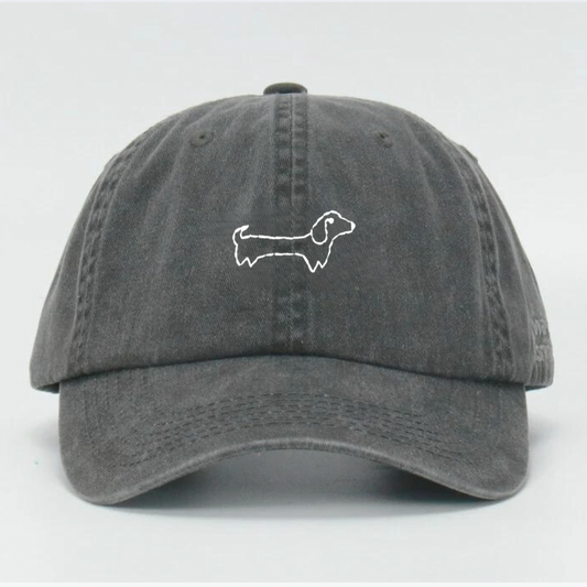 A washed black baseball cap with a hand embroidered white 'Wiener' feature on the front and an adjustable strap at the back.