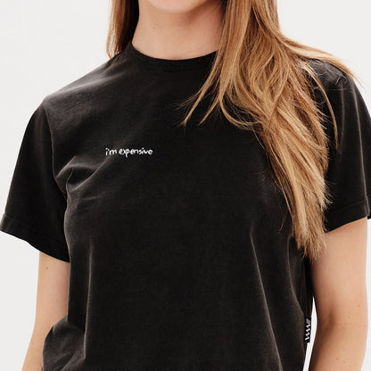Woman wearing a black t-shirt with an I'm expensive embroidery