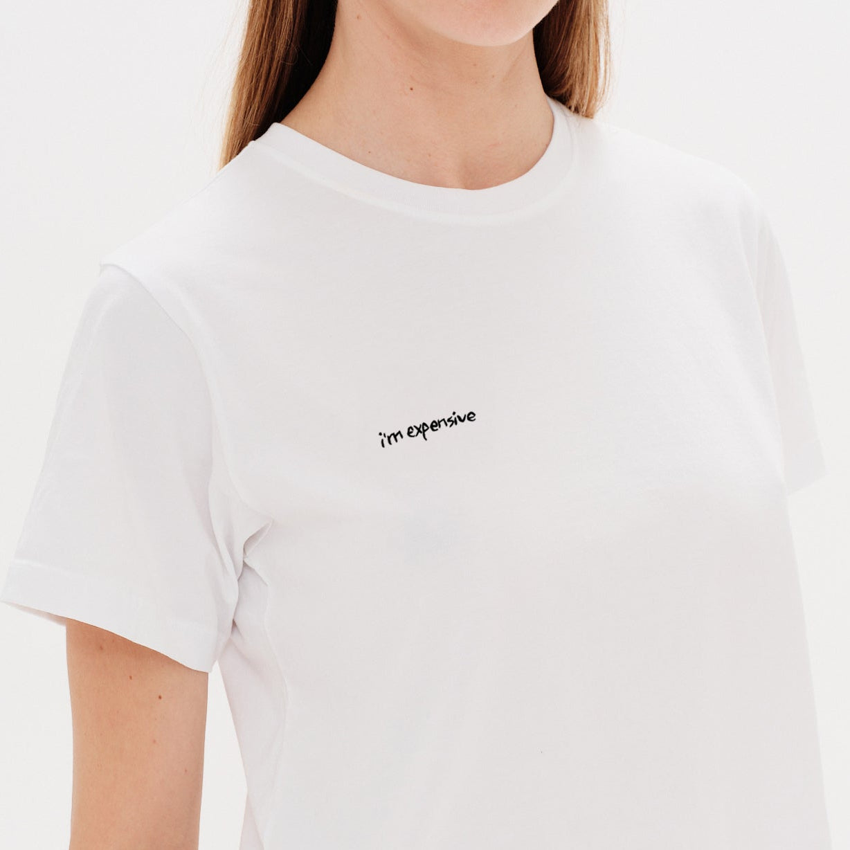 Woman wearing a white t-shirt with an I'm expensive embroidery