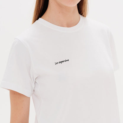 Woman wearing a white t-shirt with an I'm expensive embroidery