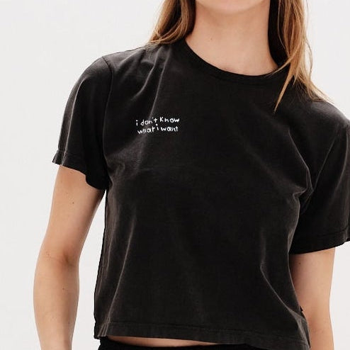 Woman wearing a black t-shirt with an I Don't Know What I Want embroidery