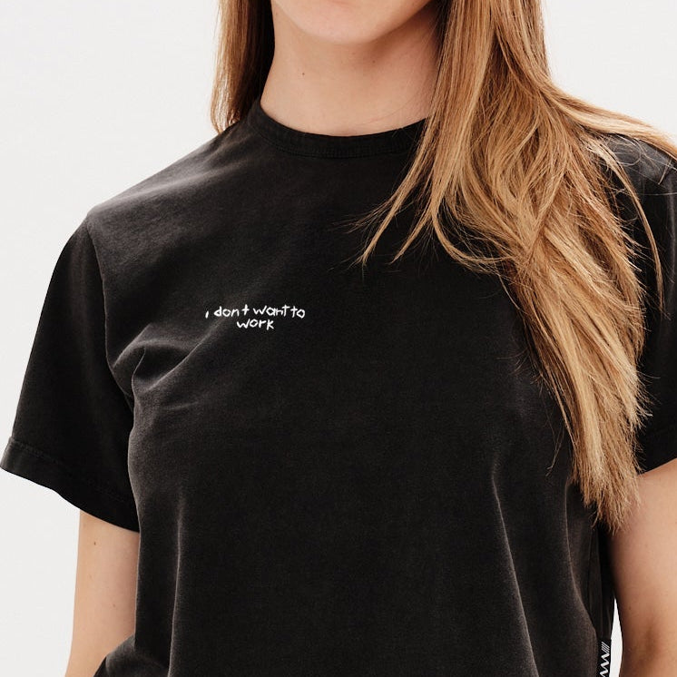 Woman wearing a black t-shirt with an I don't want to work embroidery