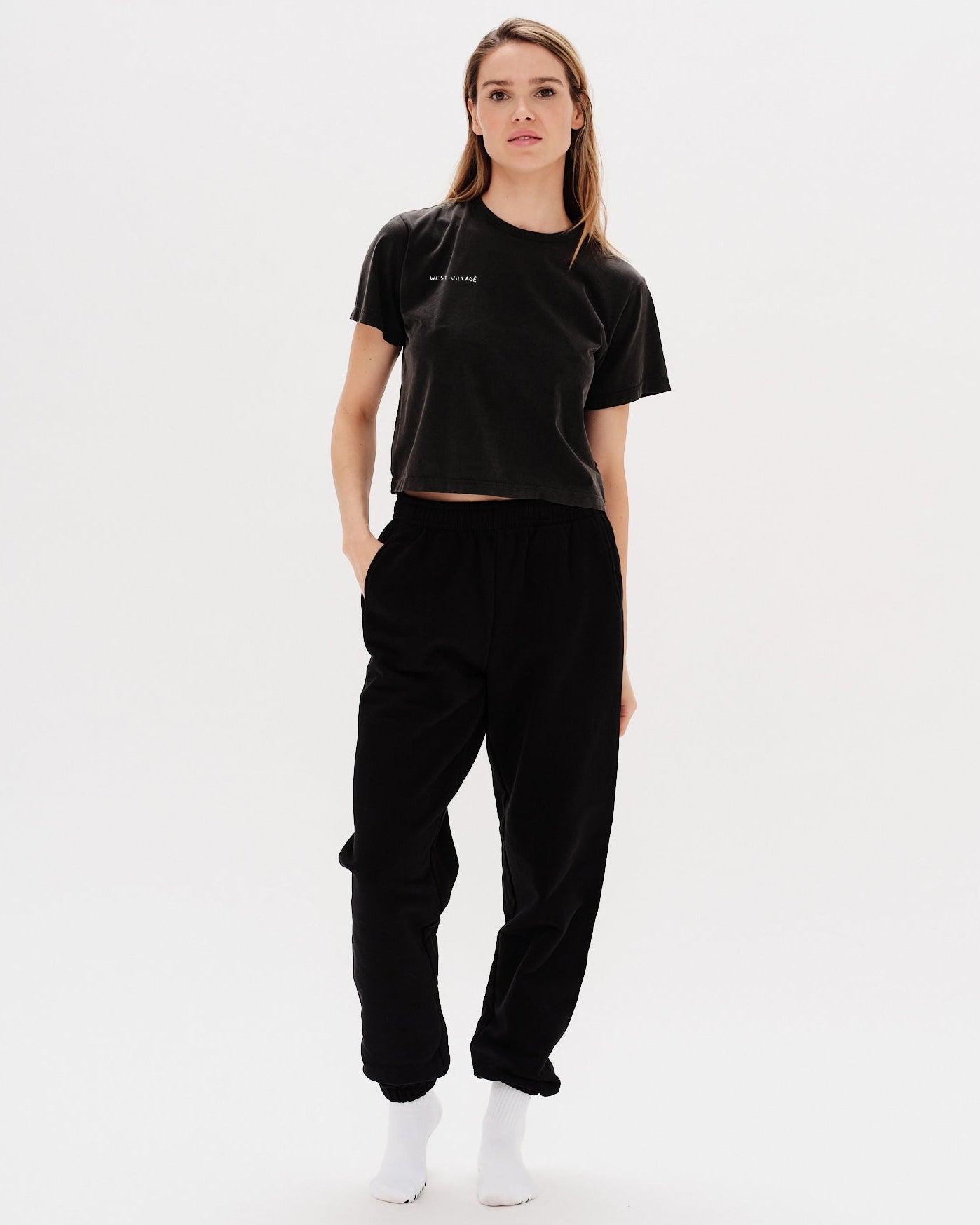Woman wearing a black t-shirt with a West Village embrodery
