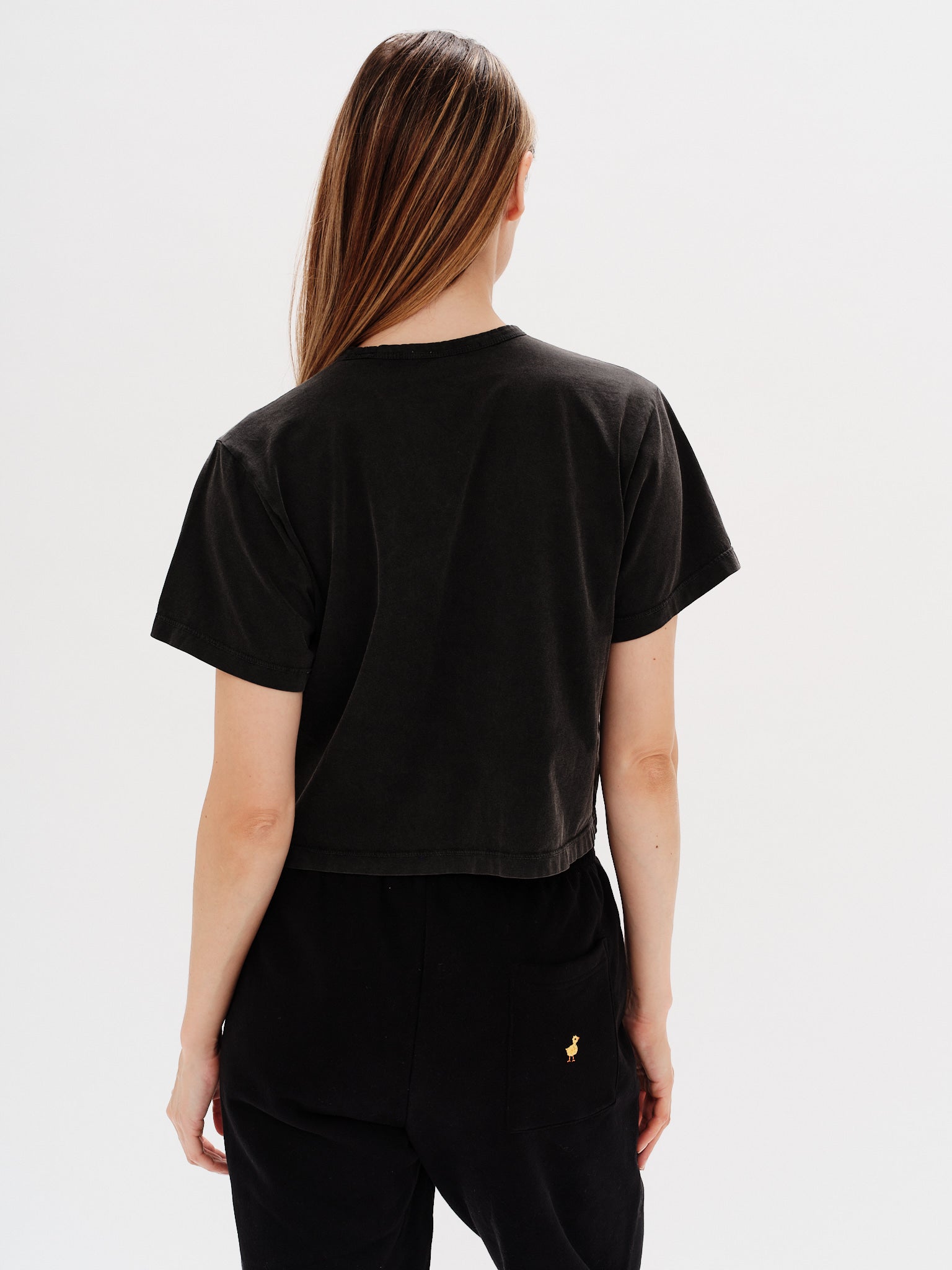 Woman wearing a black t-shirt with a West Village embrodery