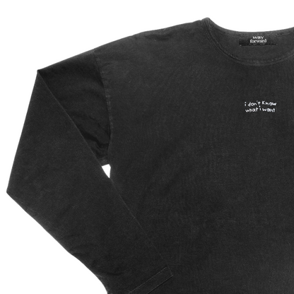 Black long sleeve crop tee with white embroidery text 'I don't know what I want' on the chest area.