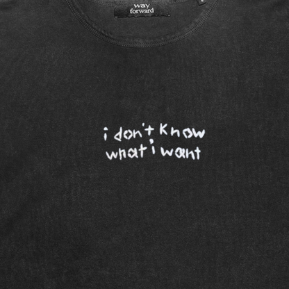 Black long sleeve crop tee with white embroidery text 'I don't know what I want' on the chest area.