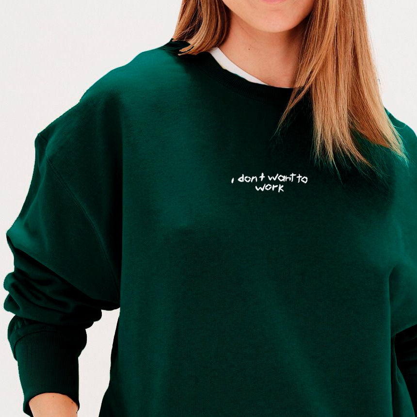 Woman wearing a green sweatshirt with an I don't want to work embroidered text