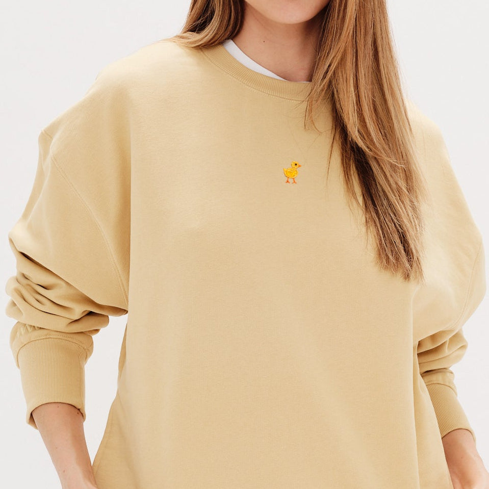Woman wearing a yellow sweatshirt with a duck embroidery