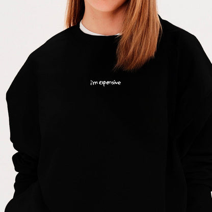 Woman wearing a black sweatshirt with an 'I'm expensive' embroidery