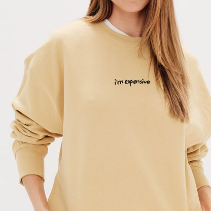 Woman wearing a yellow sweatshirt with an 'I'm expensive' embroidery