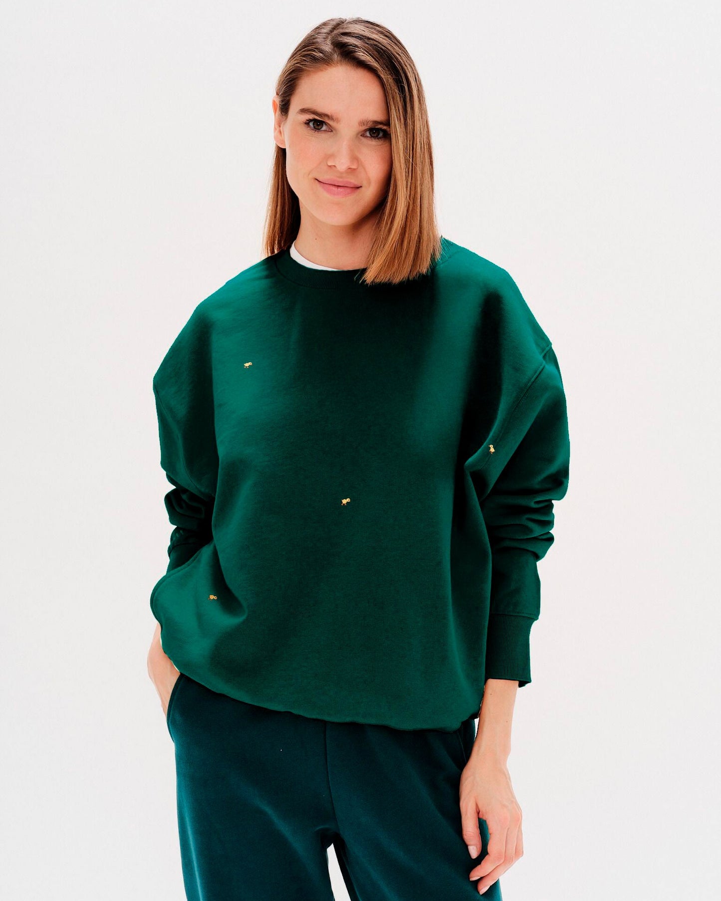 Woman wearing a green sweatshirt with ducks embroidery
