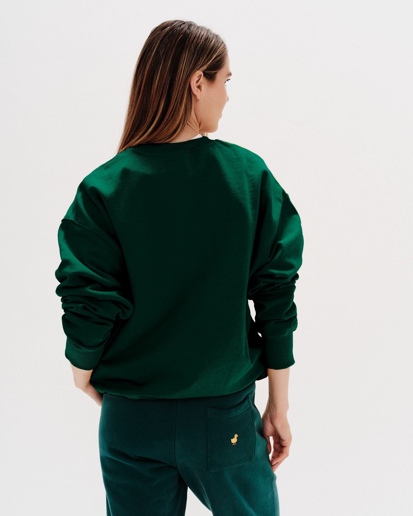Woman wearing a green sweatshirt with ducks embroidery