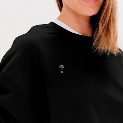 Woman wearing a black sweatshirt with a martini embroidery