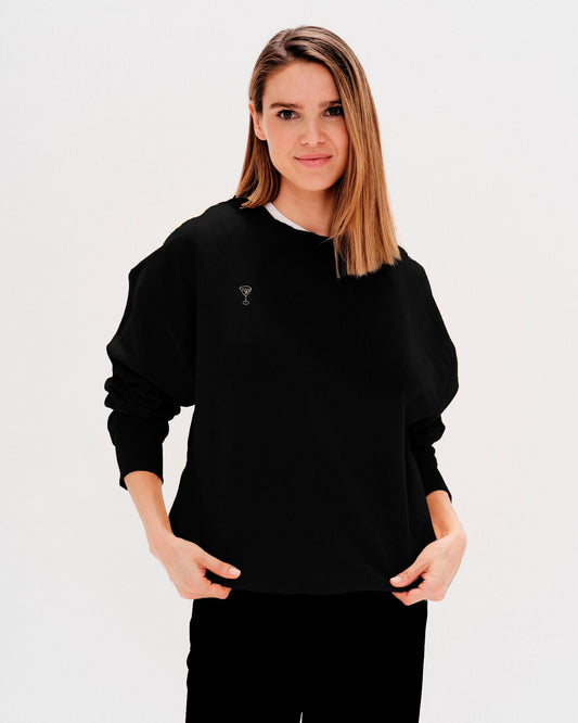 Woman wearing a black sweatshirt with a martini embroidery
