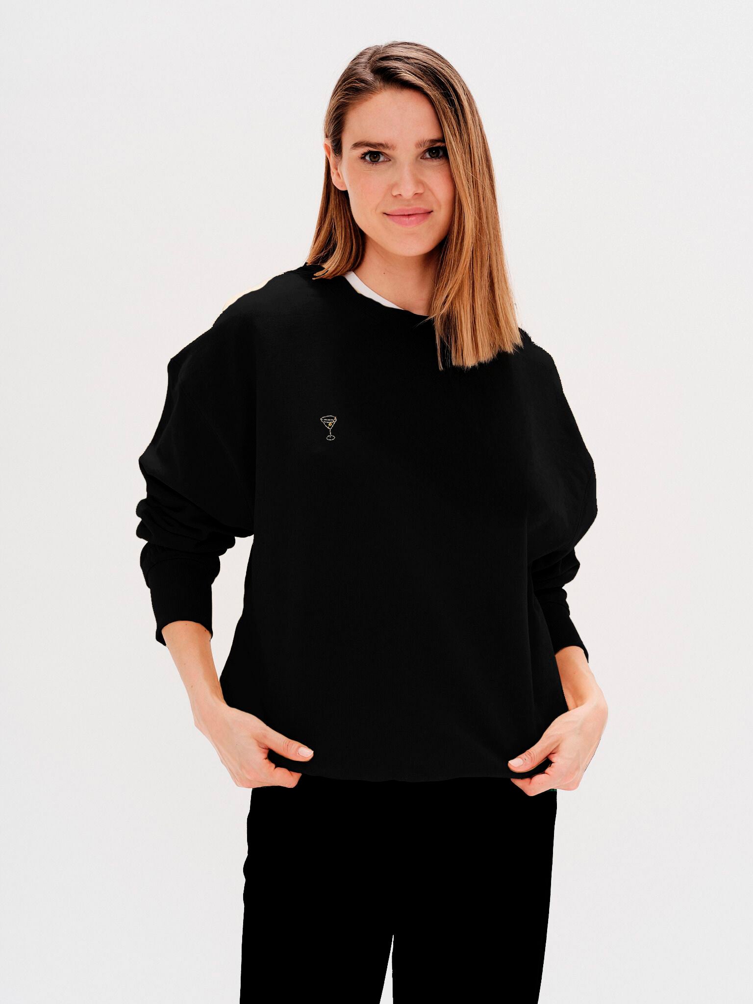 Woman wearing a black sweatshirt with a martini embroidery