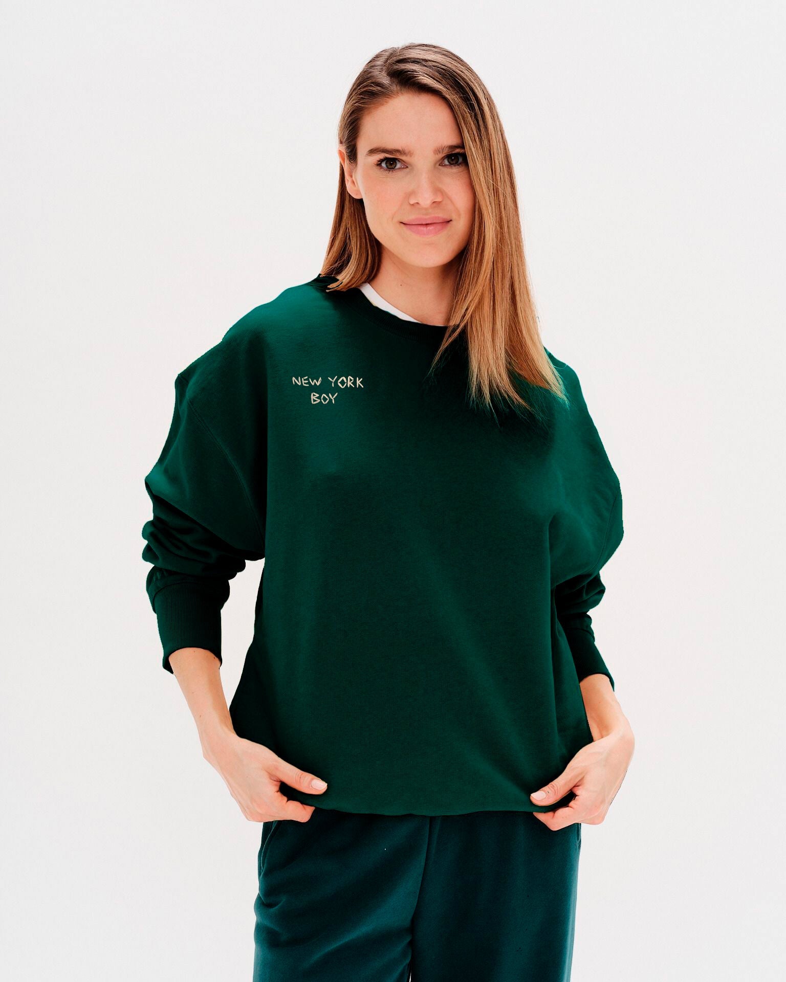 Woman wearing a green sweatshirt with New York Boy embroidered text