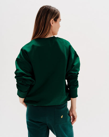Woman wearing a green sweatshirt with New York Boy embroidered text