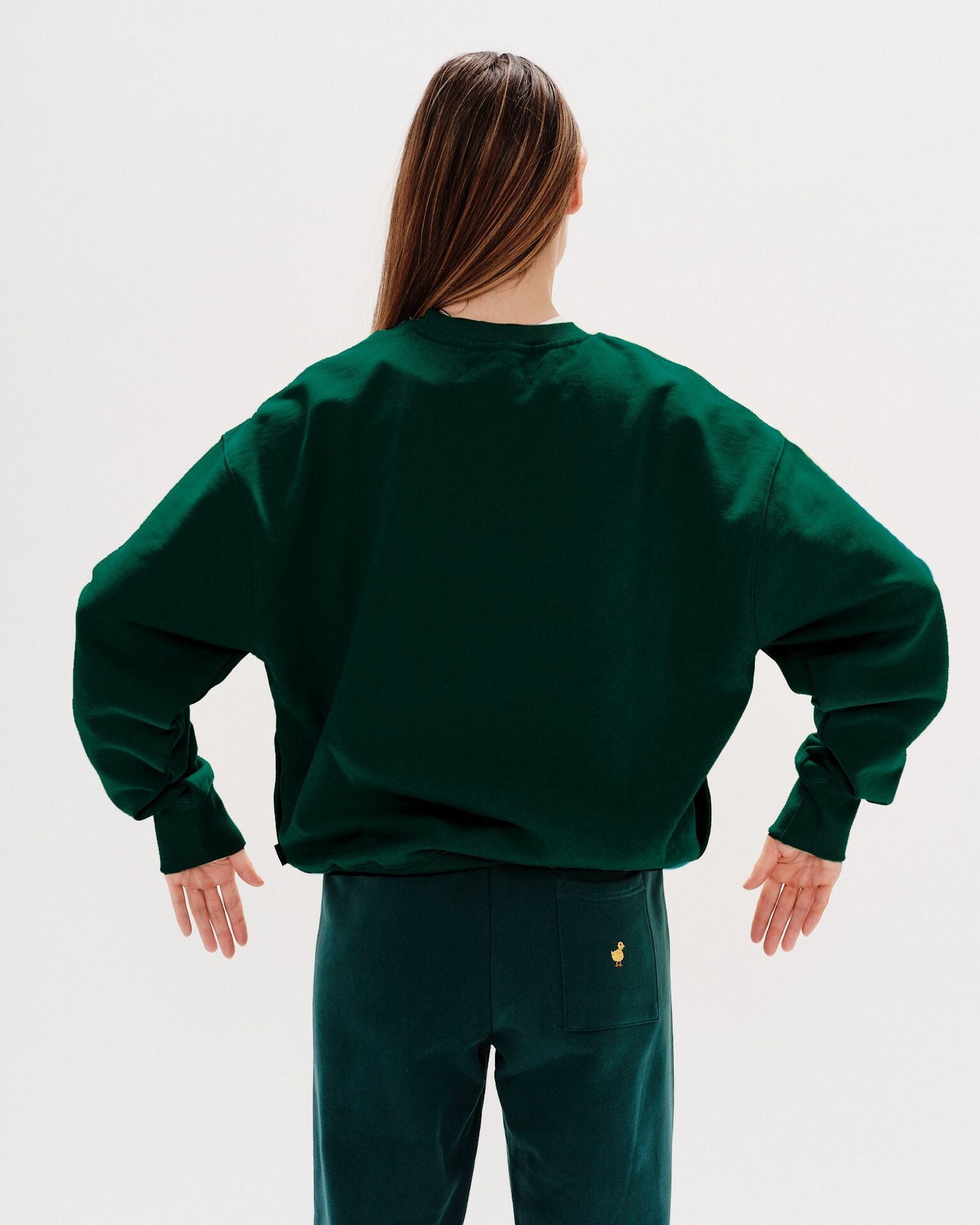 Woman wearing a green sweatshirt with a New York Girl embroidered text