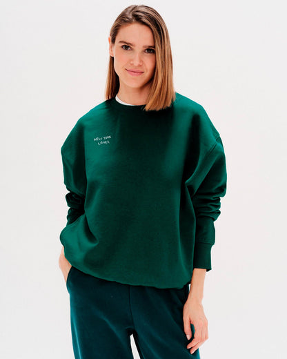 Woman wearing a green sweatshirt with New York Lover embroidered text