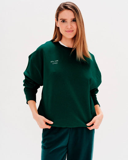 Woman wearing a green sweatshirt with New York Lover embroidered text