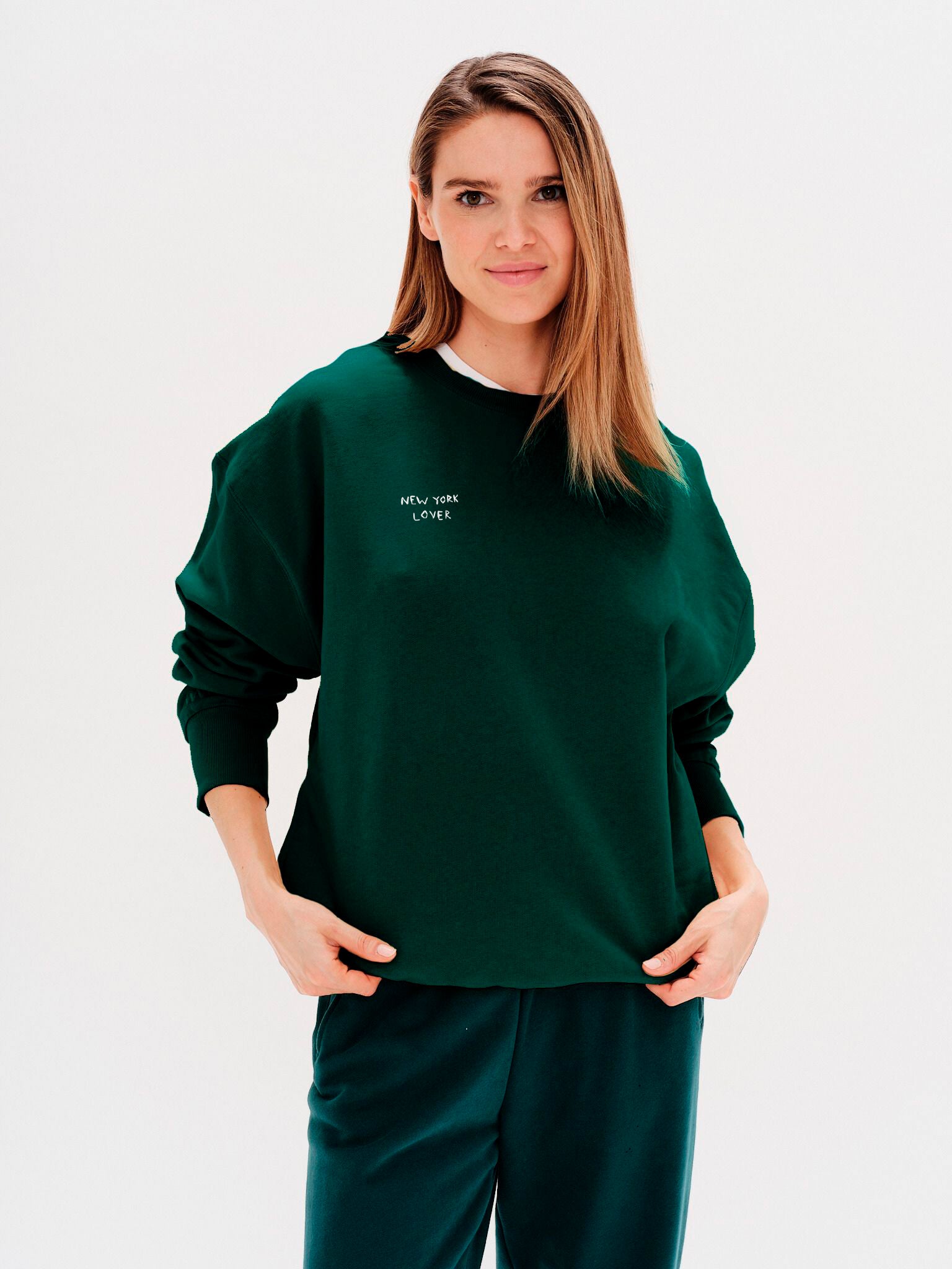Woman wearing a green sweatshirt with an New York Lover embroidered text