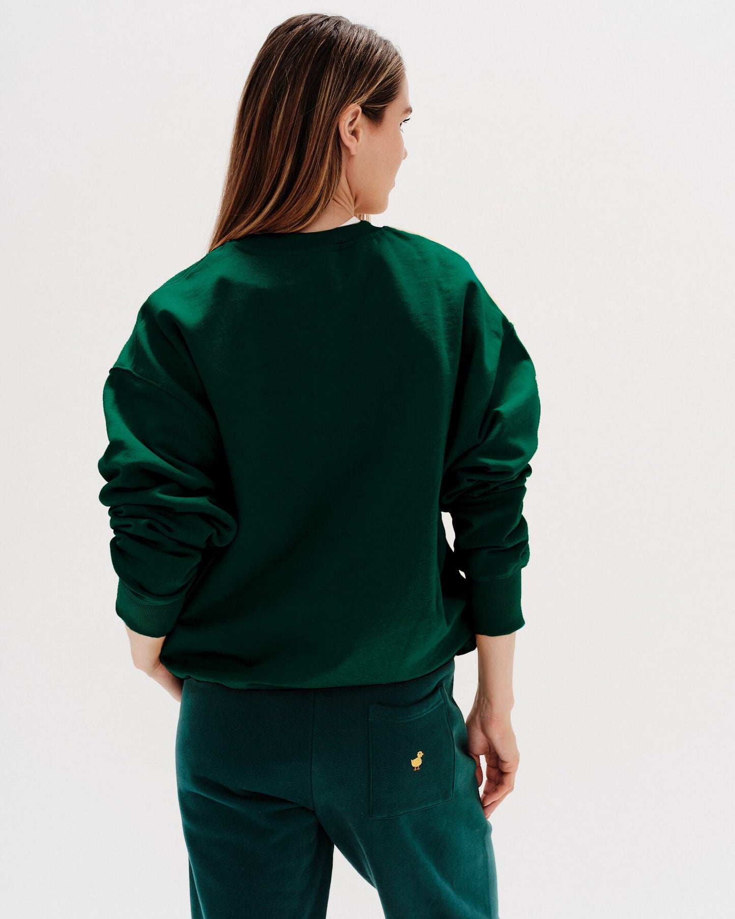 Woman wearing a green sweatshirt with New York Lover embroidered text