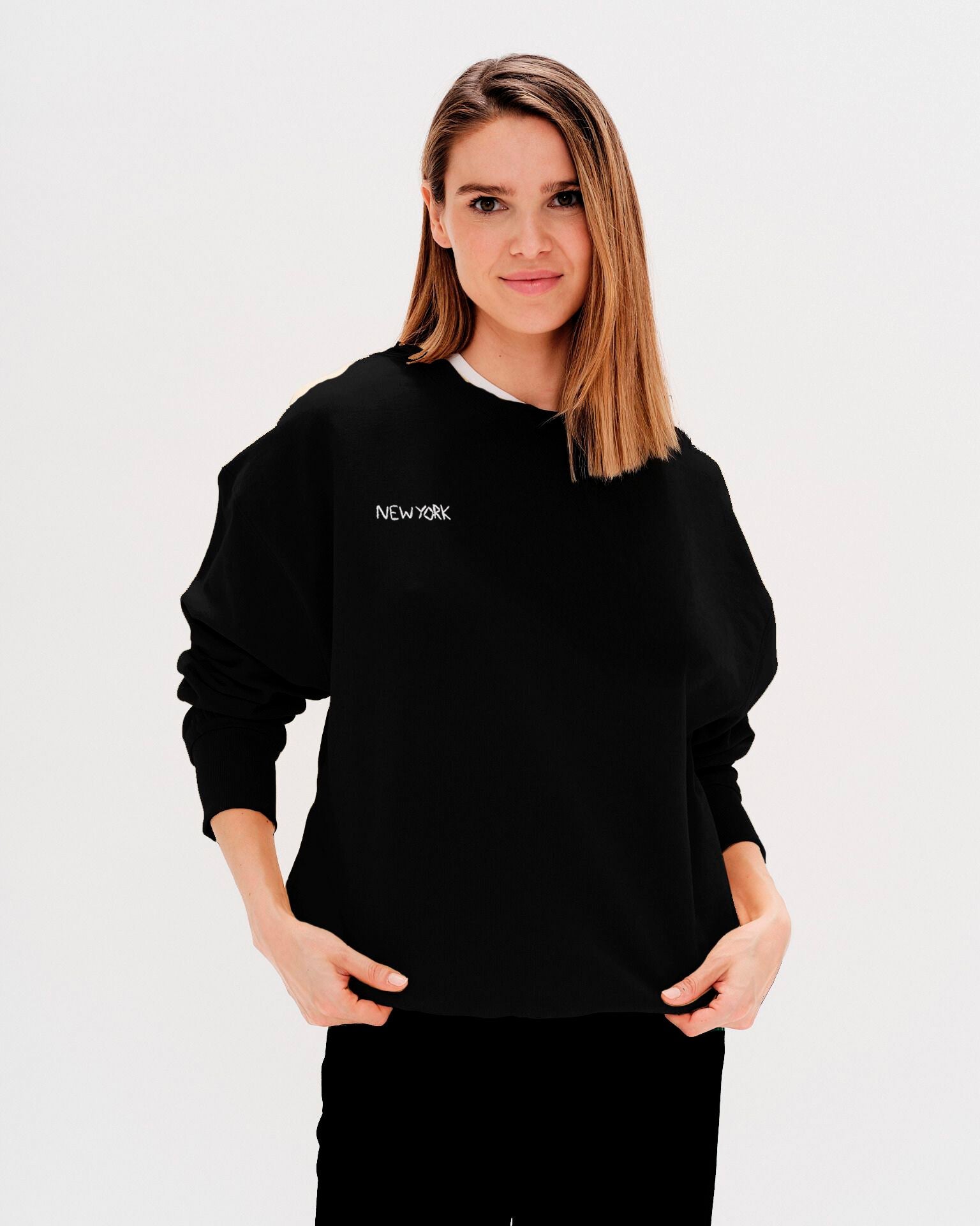Woman wearing a black sweatshirt with 'New York' embroidery