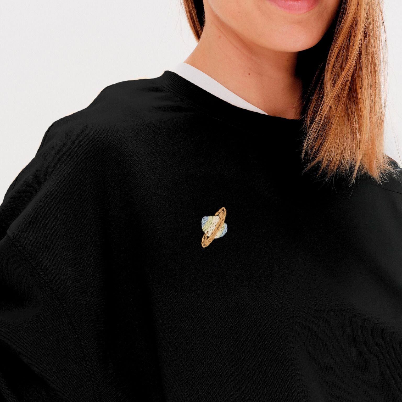 Woman wearing a black sweatshirt with a planet embroidery