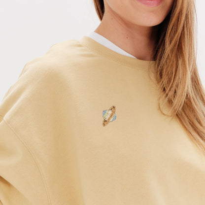Woman wearing a yellow sweatshirt with a planet embroidery