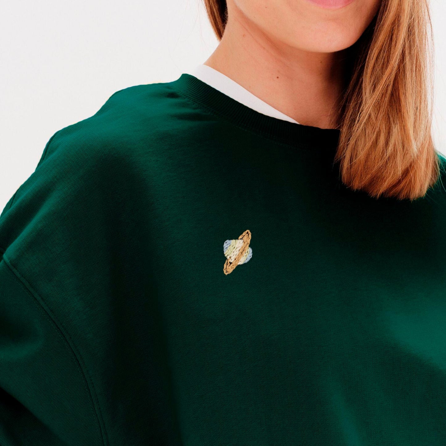 Woman wearing a green sweatshirt with a planet embroidery