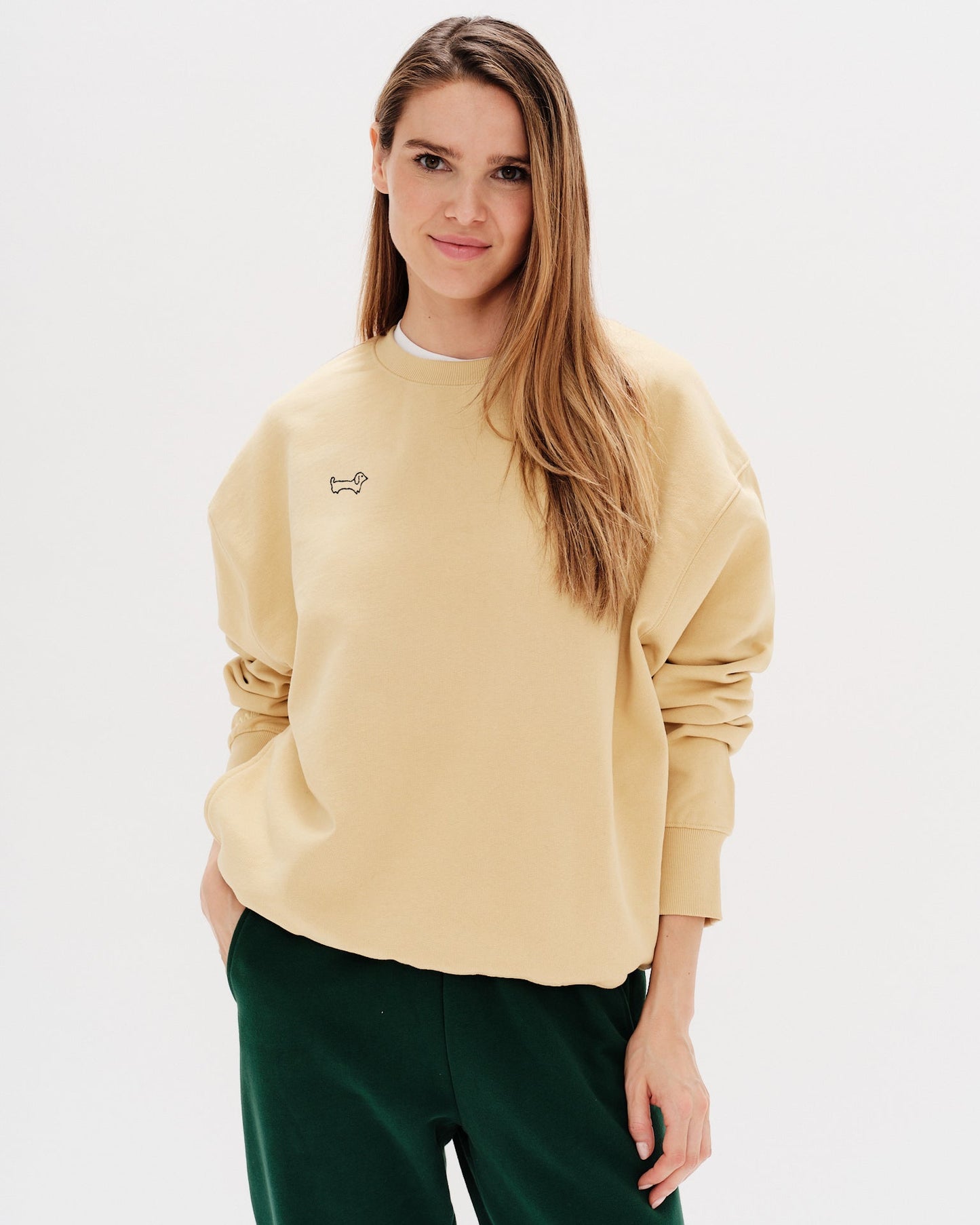 Woman wearing a yellow sweatshirt with a wiener dog embroidery