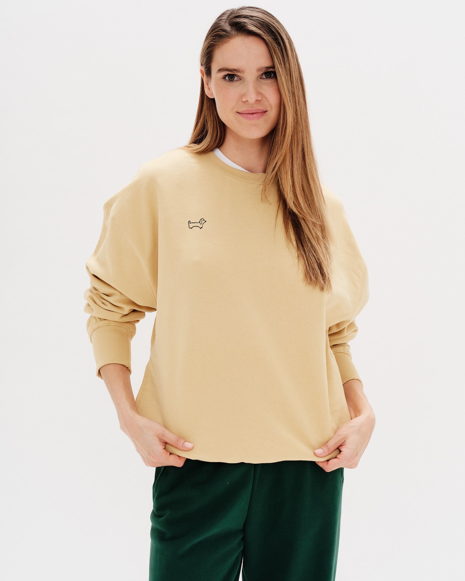 Woman wearing a yellow sweatshirt with a wiener dog embroidery
