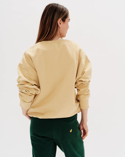 Woman wearing a yellos sweatshirt with embroidered west village text